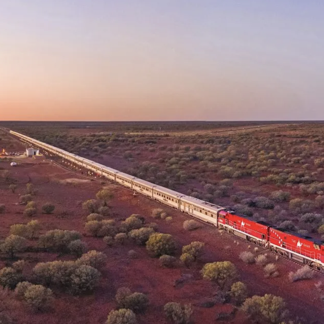 The Ghan passenger train travelling through the red landscape of the Australian Outback